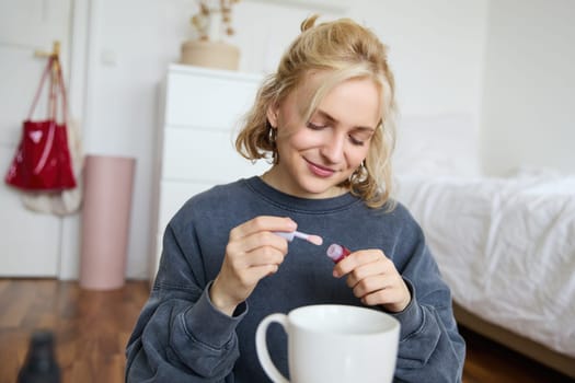 Portrait of young blond girl, puts on lip gloss while getting ready for party. Lifestyle blogger, woman content creator recording video of her with makeup.