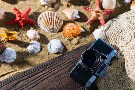 Old camera. Tourist accessories lie on the platform. Sandy shore of the sea beach.