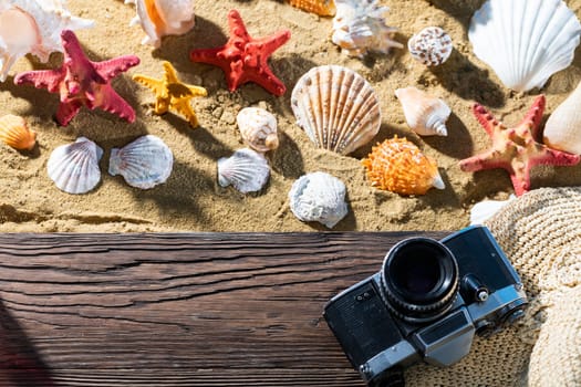 Old camera. Tourist accessories lie on the platform. Sandy shore of the sea beach.