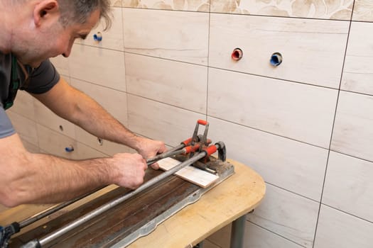 Tile cutting machine. Construction worker. Precise cutting of ceramic tiles.