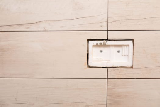 Wall covered with ceramic tiles. The hole has been prepared for the installation of buttons activating the water drain for the shell.