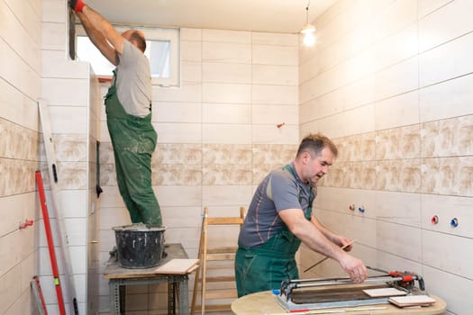 Applying cement glue to the wall with a special stainless steel trowel with teeth. An experienced construction worker.