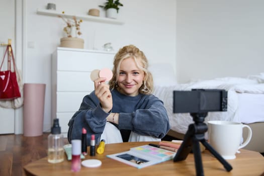 Portrait of beautiful blond woman, girl shows blushes, beauty products, recording video on digital camera, creating content for social media account, vlogger recommending items in vlog.