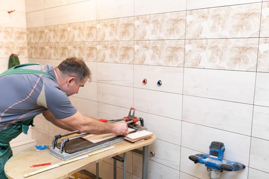 Tile cutting machine. Construction worker. Precise cutting of ceramic tiles.