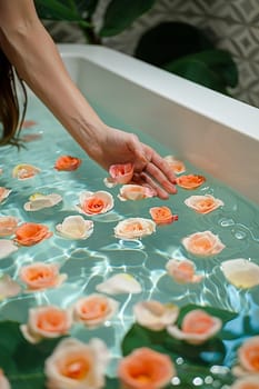 Close-up of hand sprinkling rose petals in a bath, evoking luxury and relaxation.