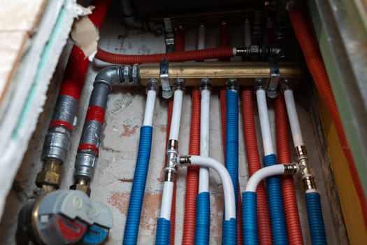 Plumbing installation in a newly designed bathroom. Water pipe in corrugated insulation in blue and red.