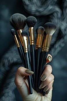 Hand holding a collection of makeup brushes, symbolizing artistry and beauty tools.