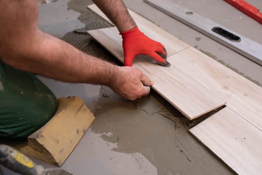 General construction worker. Adhesive for ceramic tiles. The builder glues terracotta to the floor.