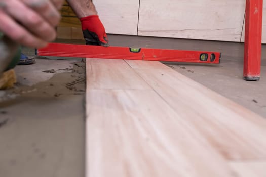 Spirit level - a device for checking the correctness of works performed in relation to the level. A professional construction worker. Kneeling.