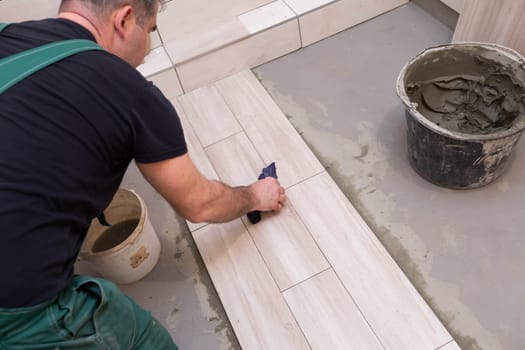 Cleaning the adhesive from ceramic tiles. Construction worker. Bathroom renovation work.