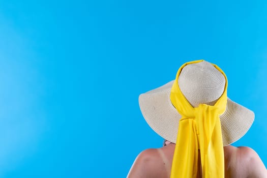 A big beach hat on his head during the hot summer against the blue sky.