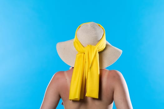 A big beach hat on his head during the hot summer against the blue sky.