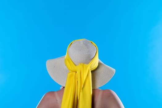 A big beach hat on his head during the hot summer against the blue sky.