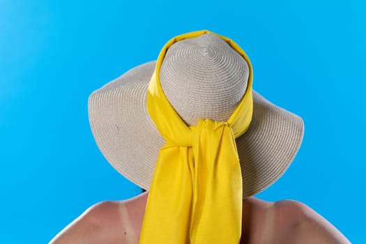 A big beach hat on his head during the hot summer against the blue sky.