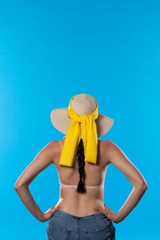 A young woman with a hat on her head and a tan on her back stands in full sun.