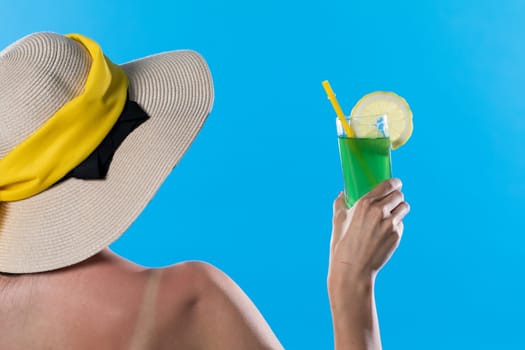 A young girl stands back to back with a cool drink in hand against the blue sky.