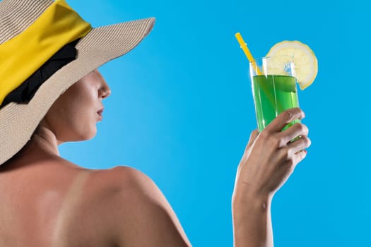 A young girl stands back to back with a cool drink in hand against the blue sky.