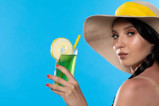 The young girl looks into the lens and holds a cold alcoholic drink in her hand.