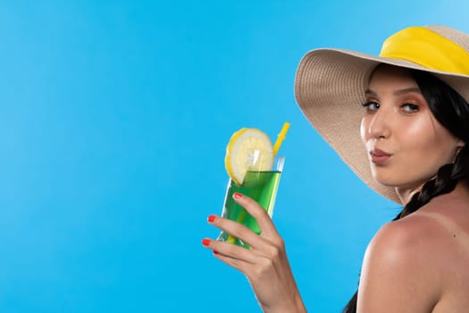 The young girl looks into the lens and holds a cold alcoholic drink in her hand.
