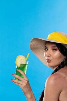 The young girl looks into the lens and holds a cold alcoholic drink in her hand.