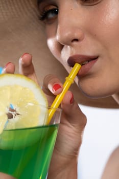 A teenager sipping a cold alcoholic drink through a straw during a hot summer.