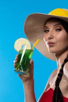 The young girl looks into the lens and holds a cold alcoholic drink in her hand.