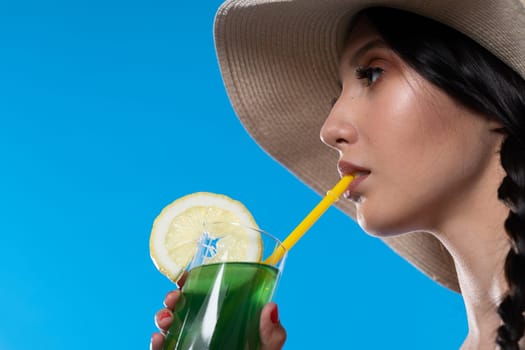 The young girl looks into the lens and holds a cold alcoholic drink in her hand.