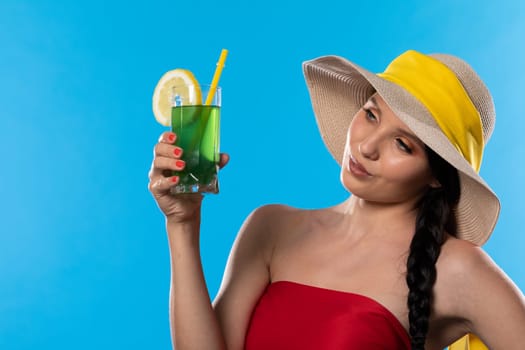 The young girl looks into the lens and holds a cold alcoholic drink in her hand.