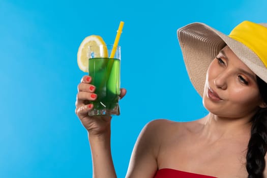 The young girl looks into the lens and holds a cold alcoholic drink in her hand.