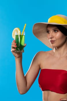 The young girl looks into the lens and holds a cold alcoholic drink in her hand.