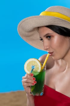The young girl looks into the lens and holds a cold alcoholic drink in her hand.