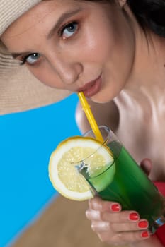 The young girl looks into the lens and holds a cold alcoholic drink in her hand.