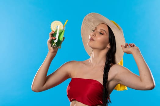 The young girl looks into the lens and holds a cold alcoholic drink in her hand.
