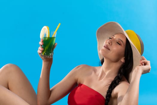 During hot summer, the teenager with a hat on her head holds an alcoholic drink in her hand.