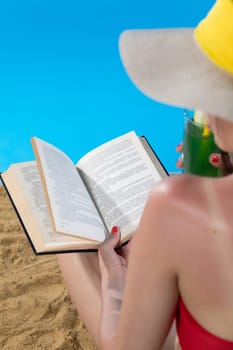 The teenager takes a sun bath and relax reading a romantic book and sipping a drink.