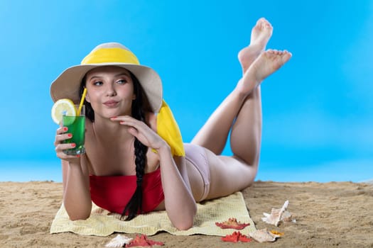 While sunbathing on the beach, a teenager drinks a cold alcoholic drink.