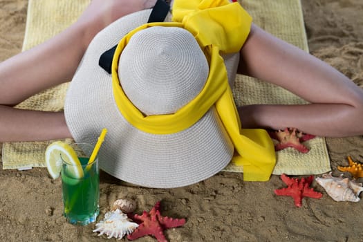 While sunbathing on the beach, a teenager drinks a cold alcoholic drink.