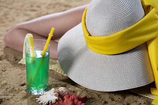 While sunbathing on the beach, a teenager drinks a cold alcoholic drink.