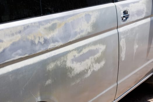 silver car side with big sun burns, coating was burned under constant sun light exposure, closeup with selective focus