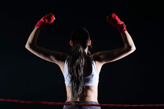 The fighter won her first fight. The woman raised her hands in evidence of winning the fight.