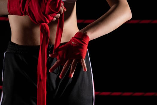 A woman prepares for an fight, wrapping her hands in a special boxing bandage. Strong woman. The inevitable fight in the ring.