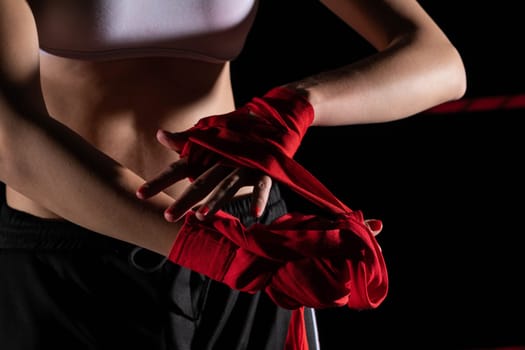 A woman prepares for an fight, wrapping her hands in a special boxing bandage. Strong woman. The inevitable fight in the ring.