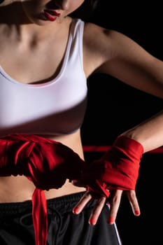 A woman prepares for an fight, wrapping her hands in a special boxing bandage. Strong woman. The inevitable fight in the ring.
