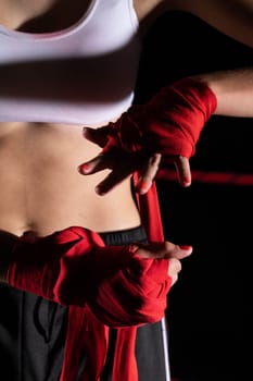 A woman prepares for an fight, wrapping her hands in a special boxing bandage. Strong woman. The inevitable fight in the ring.