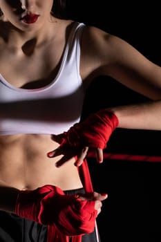 A woman prepares for an fight, wrapping her hands in a special boxing bandage. Strong woman. The inevitable fight in the ring.