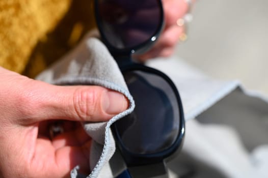 female hands wiping sunglasses with a napkin
