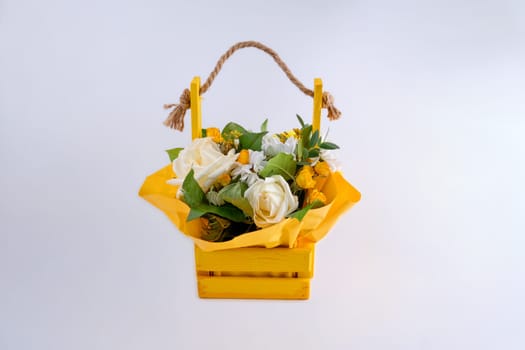 A bouquet of fresh flowers in a wooden basket on a light background