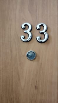 numbers 33 on a white exterior apartment door, symbol objects, sky. High quality photo