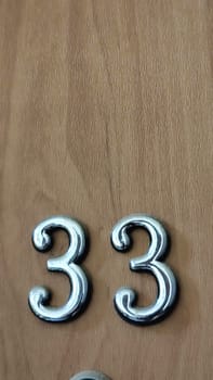 numbers 33 on a white exterior apartment door, symbol objects, sky. High quality photo