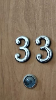 numbers 33 on a white exterior apartment door, symbol objects, sky. High quality photo